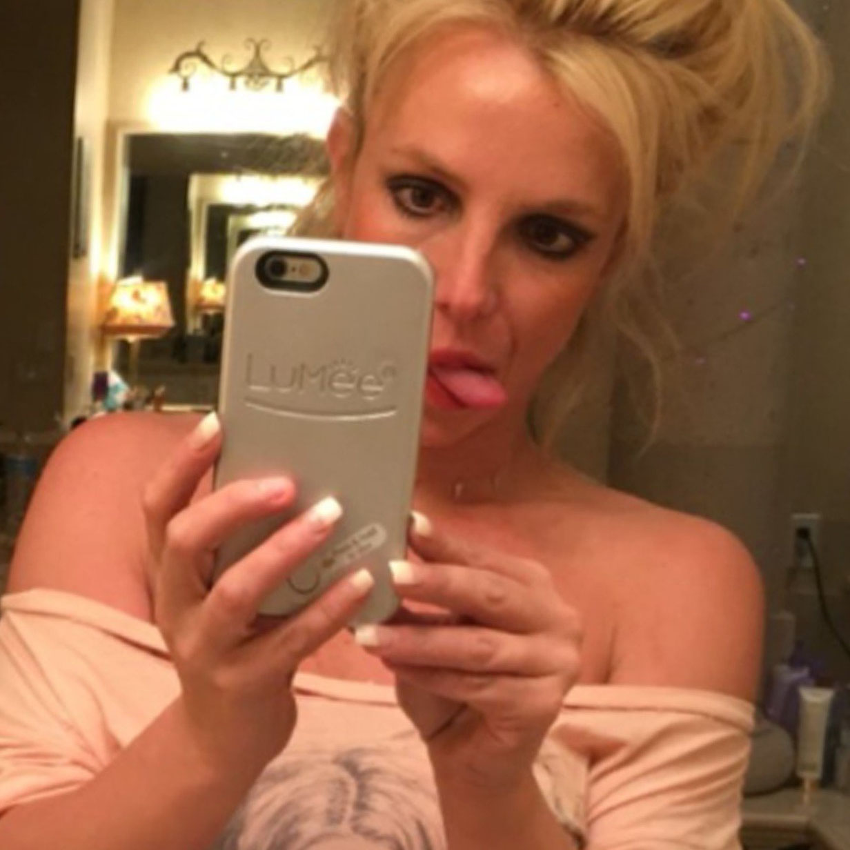 Britney Spears taking a mirror selfie with her phone while sticking her tongue out